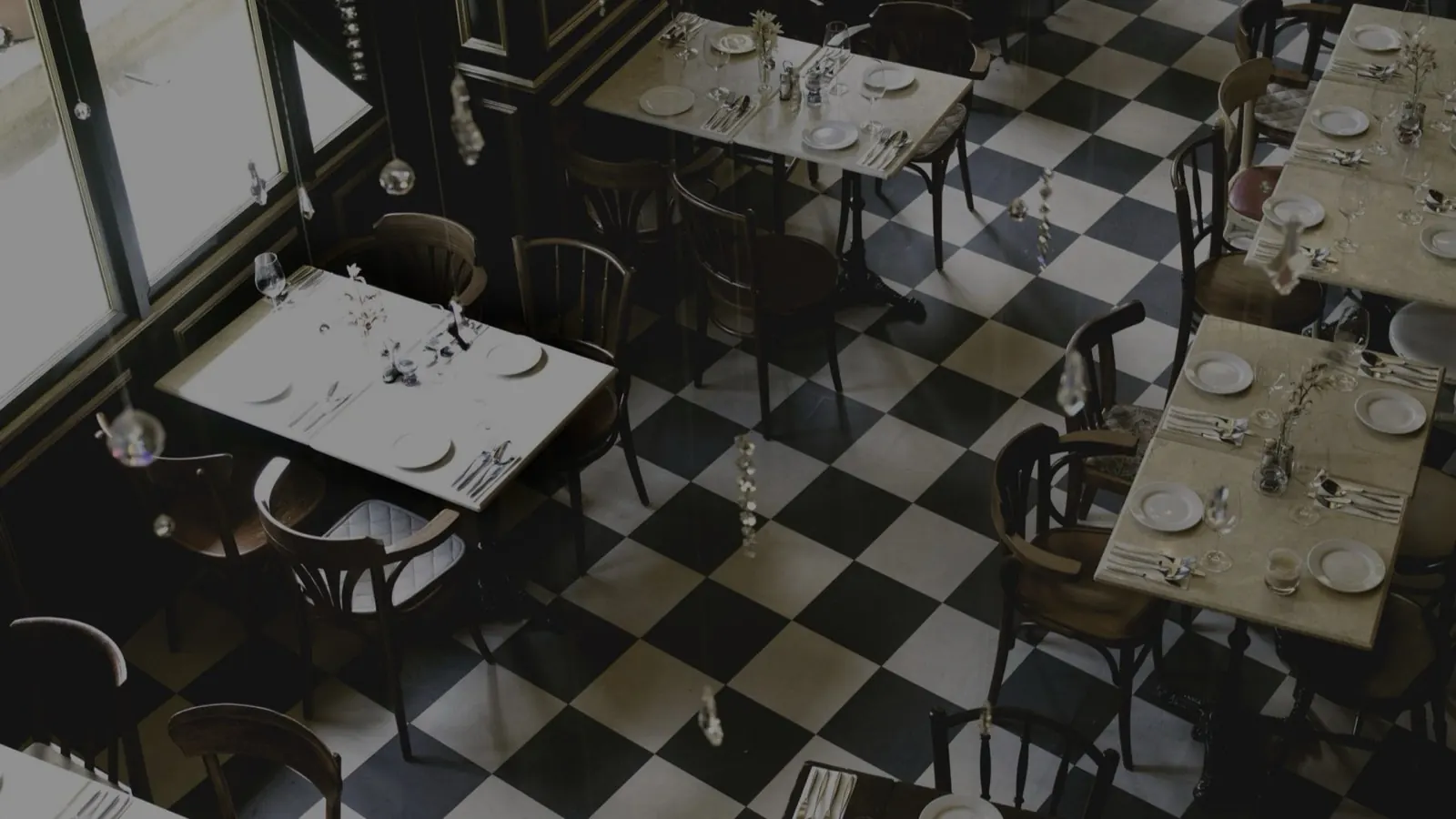 The dining room seen from above, tables laid with white linen across a black and white checkerboard floor