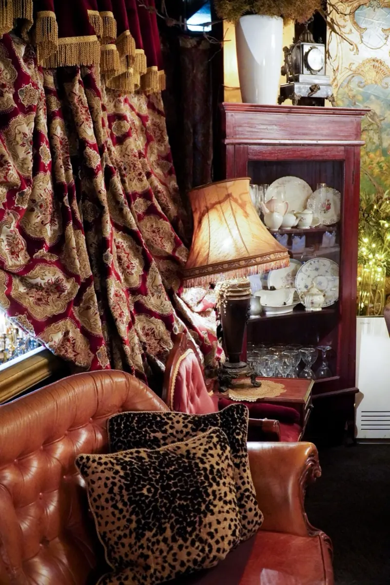 A corner of the dining room, gold-framed mirrors above white-linen tables